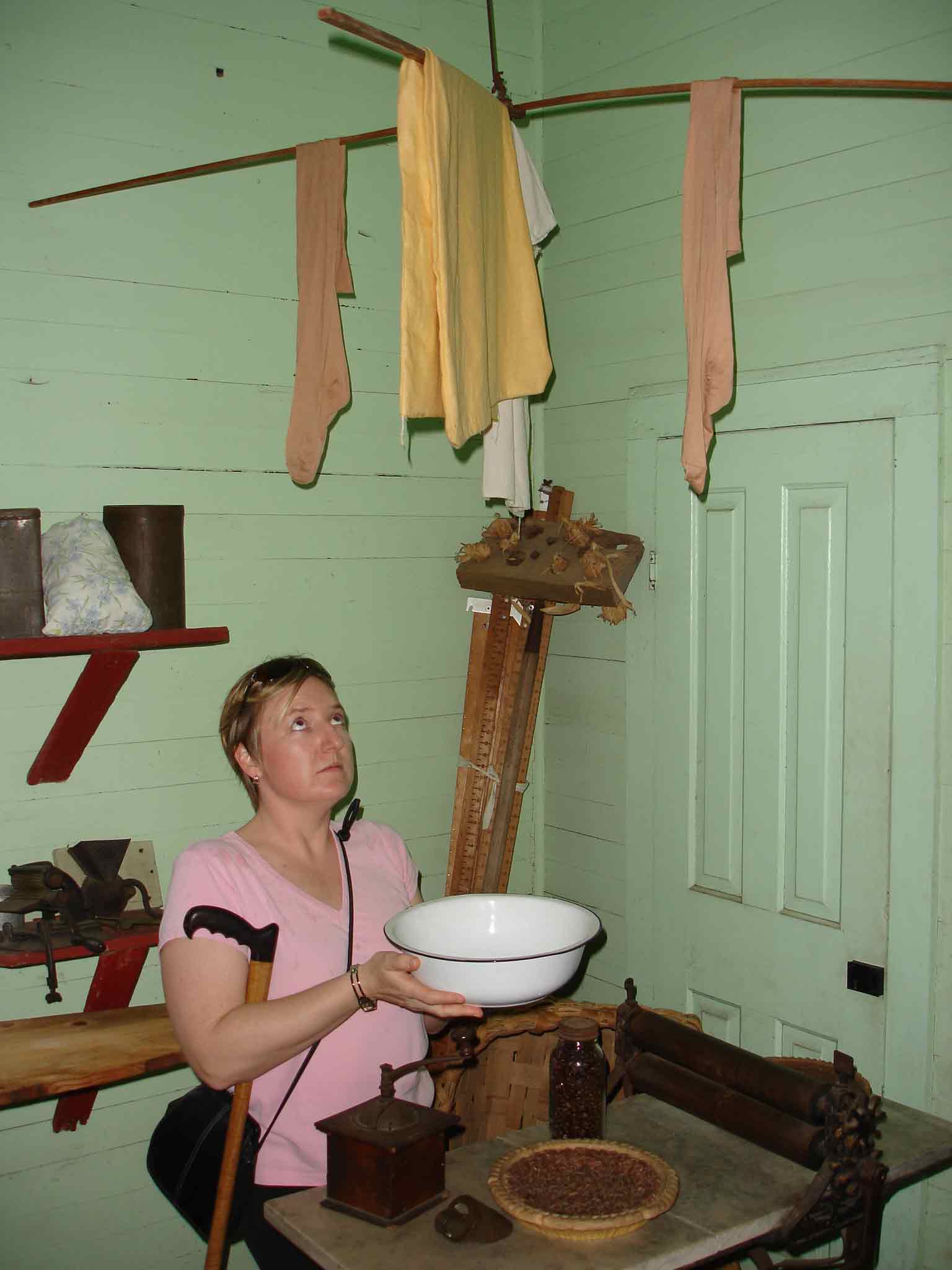 Carrie holding a washing bowl beneath clothes hanging out to dry in the slave home
